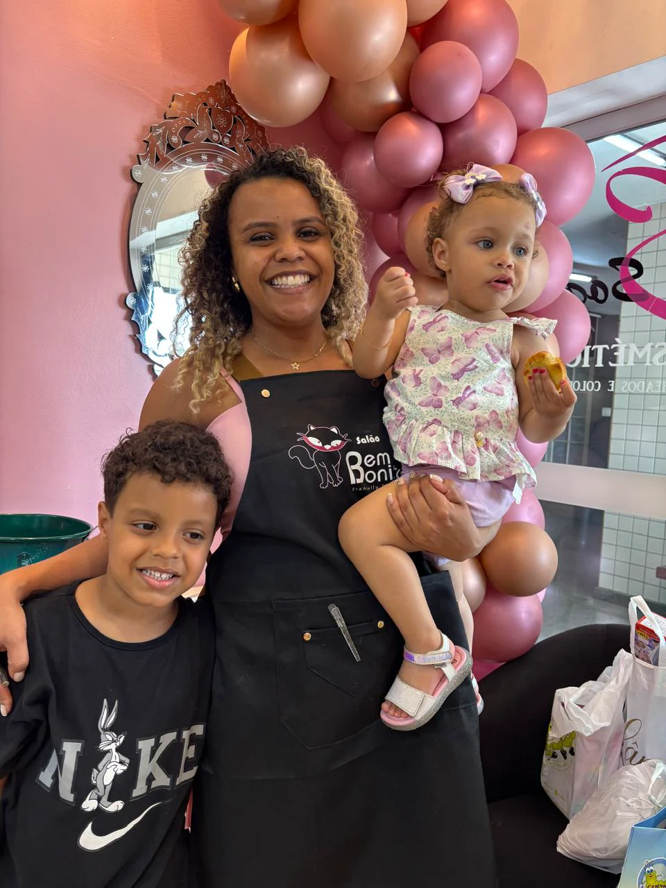 Francielly com duas crianças durante a comemoração, ao lado dos balões do salão